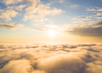 Fototapeta premium Aerial view White clouds in blue sky. Top view. View from drone. Aerial bird's eye view. Aerial top view cloudscape. Texture of clouds. View from above. Sunrise or sunset over clouds