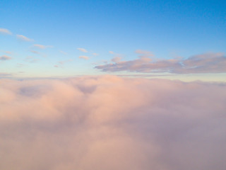 Fototapeta premium Aerial view White clouds in blue sky. Top view. View from drone. Aerial bird's eye view. Aerial top view cloudscape. Texture of clouds. View from above. Sunrise or sunset over clouds