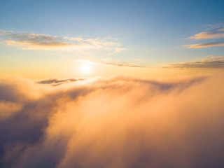 Fototapeta premium Aerial view White clouds in blue sky. Top view. View from drone. Aerial bird's eye view. Aerial top view cloudscape. Texture of clouds. View from above. Sunrise or sunset over clouds