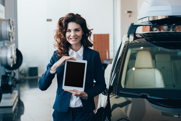 smiling businesswoman holding digital tablet with blank screen and looking at camera