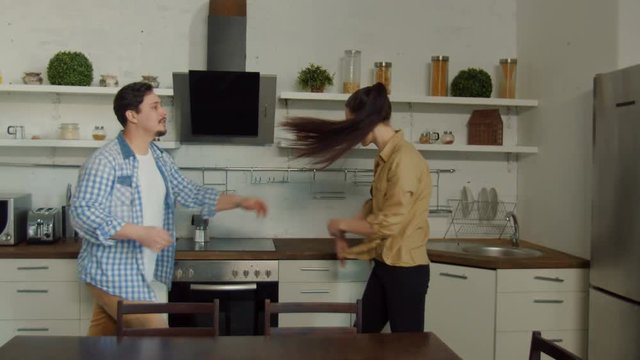 Young couple quarreling in domestic kitchen, blinded by jealousy husband shouting, pushing wife, blaming in adultery. Angry woman slapping man during fighting irritated by unfounded accusations.