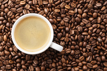 Coffee cup on roasted coffee beans. Top view.