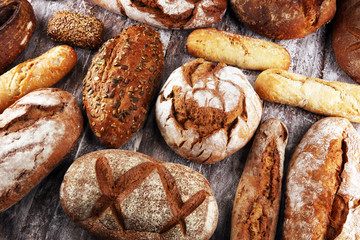 Different kinds of bread and bread rolls on board from above. Kitchen or bakery