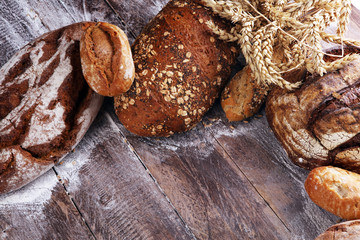 Different kinds of bread and bread rolls on board from above. Kitchen or bakery