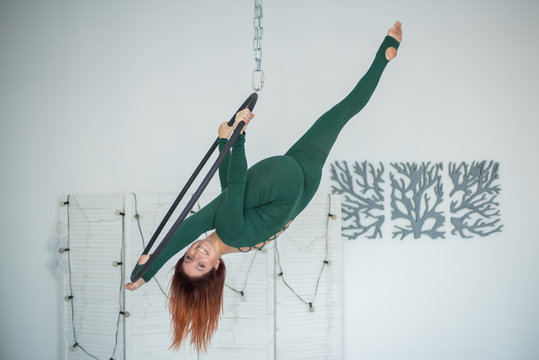 Beautiful and graceful aerial gymnast performs exercises on the air ring. Aerialist. Woman on aerial hoop