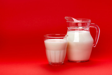 Jar and glass of milk isolated on red background with copy space for text, dairy product concept