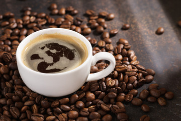 Coffee cup on roasted coffee beans. Sun rays in the background.