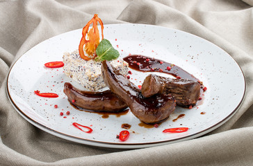 Veal tongue with garnish on white plate, on textile background