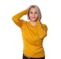 Obraz na płótnie Canvas Middle aged blonde emotionally posing in a studio. Happy woman in yellow bright sweater on white background
