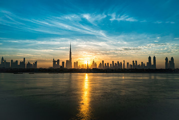 Fototapeta na wymiar Sunrise in Dubai, dawn over Burj Khalifa. Morning in Dubai, Sun over buildings. Solar path on sea comes from Burj Khalifa