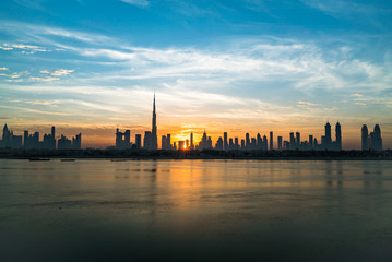 Morning or sunrise in Dubai. Dawn over Burj Khalifa. Beautiful colored cloudy sky over downtown Dubai. Solar path on sea comes from Burj Khalifa