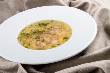 Chicken soup on a white plate on a textile background