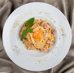 Spaghetti Carbonara on white plate on textile background