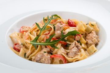 Tagliatelle with rabbit and pepper, with cream sauce in a white plate. On textile background