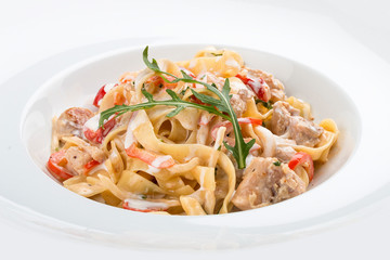 Tagliatelle with rabbit and pepper, with cream sauce in a white plate. On textile background