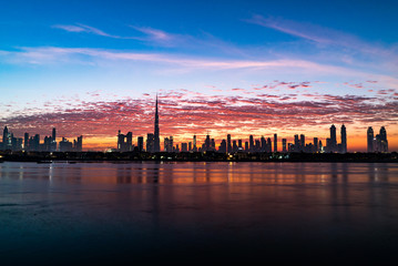 Obraz na płótnie Canvas Morning, sunrise or dusk in Dubai. Dawn over Burj Khalifa. Beautiful colored cloudy sky over Dubai downtown . Glow over buildings or skyscrapers