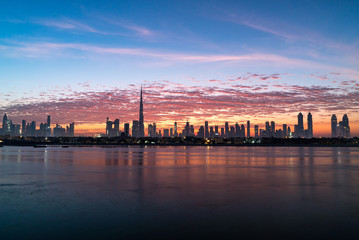 Fototapeta na wymiar Morning, sunrise or dusk in Dubai. Dawn over Burj Khalifa. Beautiful colored cloudy sky over Dubai downtown . Glow over buildings or skyscrapers
