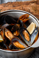 Mussel shells in a gray cauldron in tomato sauce, french fries and croutons on a gray background. Close up. Space