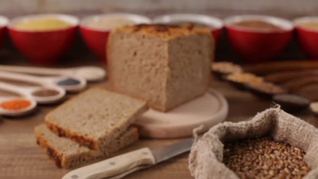 Whole food concept - wholemeal bread in center with various seeds and grains around. Camera push in, refocus from wheat to bread loaf.