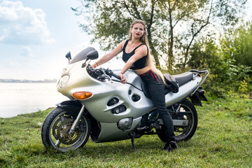 Naklejka na ściany i meble Attractive woman walks on motorbike in summer