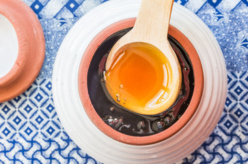 Raw African honey in a honey jar with wooden spoon on ethnic blue cloth