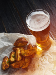 A glass of cold light beer on a wooden table and fries by country