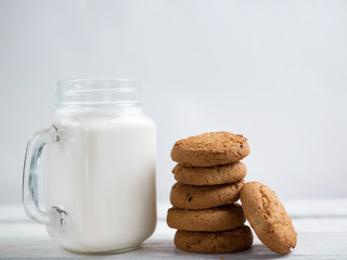 Milk and cookies on a wooden white table