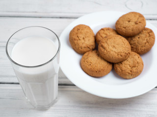 Glass of milk and cookies on wooden white background