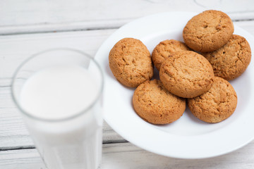 Glass of milk and cookies on wooden white background