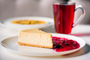 piece of cheesecake with berry jam on a white plate in the restaurant. close up. space