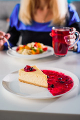 piece of cheesecake with berry jam on a white plate in the restaurant. close up. blure. space.