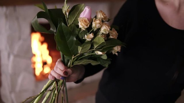 Unrecognizable female florist holding a half made bouquet and adding flowers to composition. Designing, floral workshop, leisure. Blurred picture of fireplace on the background