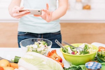 Obraz na płótnie Canvas Food blogger. Healthy nutrition. Fresh vegetables salad bowls. Female with smartphone cropped shot.