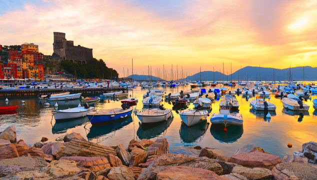 colorful boats and seascape, old castle against  cloudy warm sky with sunset  in Lerici in Liguria, Italy