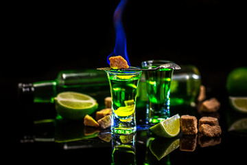 absinthe shots with sugar cubes. absinthe poured into a glass. bottle of absinthe with brown sugar and lime isolated on black background. space for text