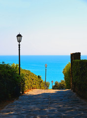 View on the narrow street and city lamps of old village Castiglione della Pescaia with mediterranean sea in background 