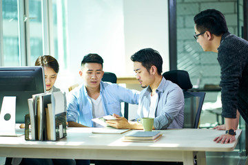 four young asian entrepreneurs discussing business in office