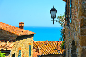  Narrow street with view on the roofs and city lamp of old village Castiglione della Pescaia with...