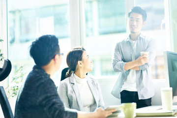 three young asian business people chatting in office