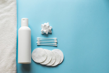 Fototapeta na wymiar Flat lay composition with white bottle, cotton swabs and pads, flower , towel on blue background. body skin care concept . copy space