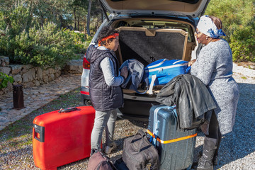 woman loading suitcases in the car, with her son, a lot of baggage