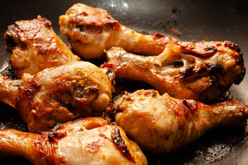 Roasted chicken legs on the black background. Top view.