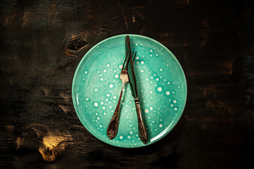 Empty rustic plate with fork and knife. Aerial view, with copy space. Aerial view, with copy space
