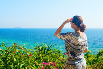 Woman on vacation looks at the sea and tropical islands on a sunny day.
