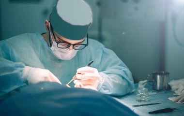 work of the surgeon in the hospital operating room. concentrated doctor with glasses.