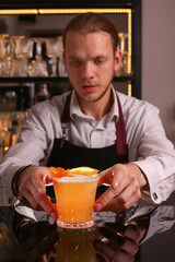 Fototapeta na wymiar Whiskey Sour alcohol cocktail with orange slice and ice cubes on black mirror background made by man bartender