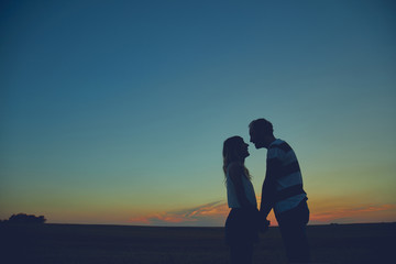 Silhouettes of a couple in sunset / sunrise time.