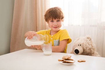 child boy drinks milk and eats cookies home kitchen 