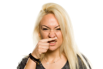 young blonde have itching in her nose on white background