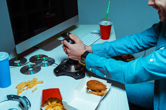 partail view of cyber sportsman holding joystick and playing video game